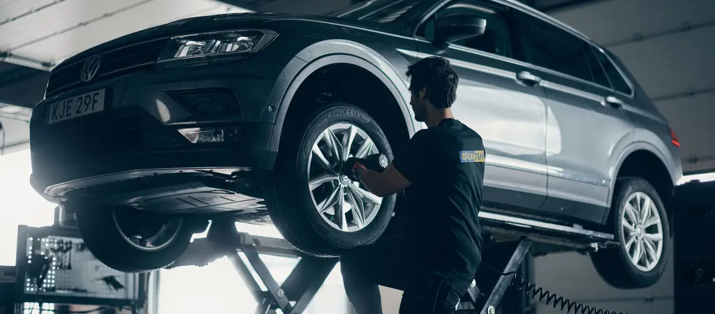 Däckmontör monterar däck på upphissad bil